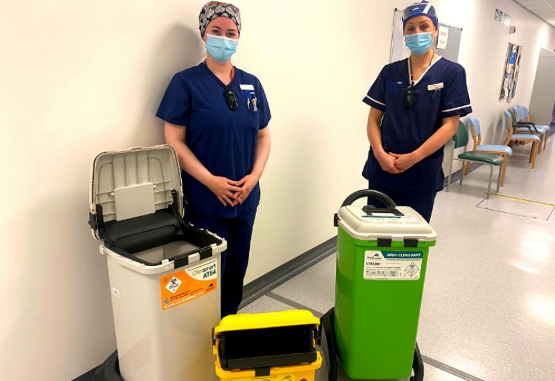 Two nurses against a white background with recycling bins for sustainability